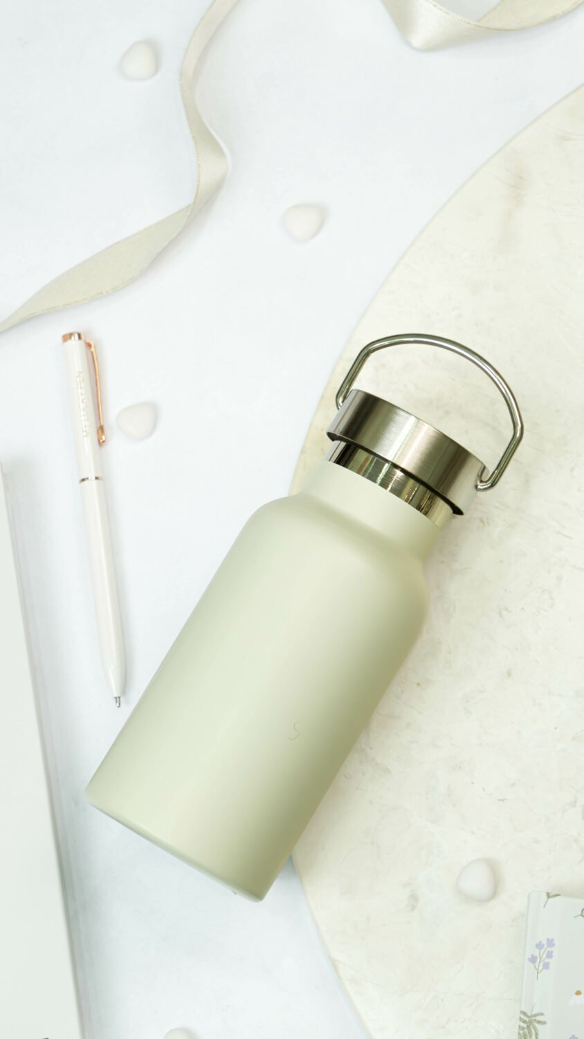 1. SEIK beige stainless steel water bottle with handle, shown on a marble surface with pen and ribbon