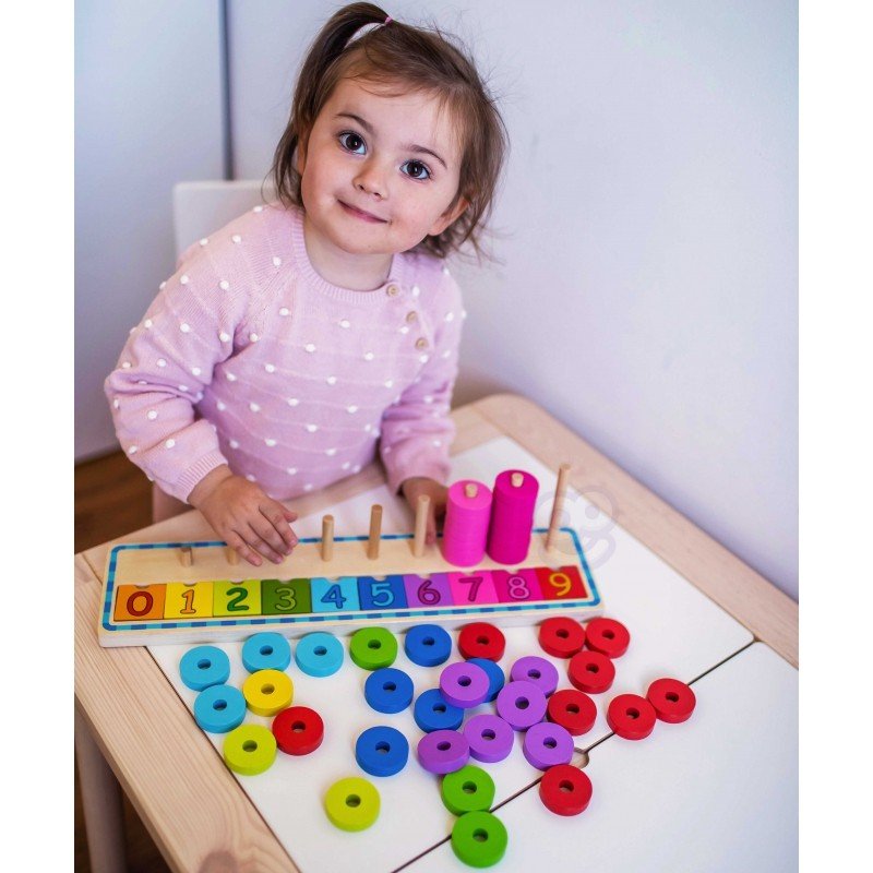 8. Child in pink polka dot sweater playing with colorful wooden counting puzzle at a table
