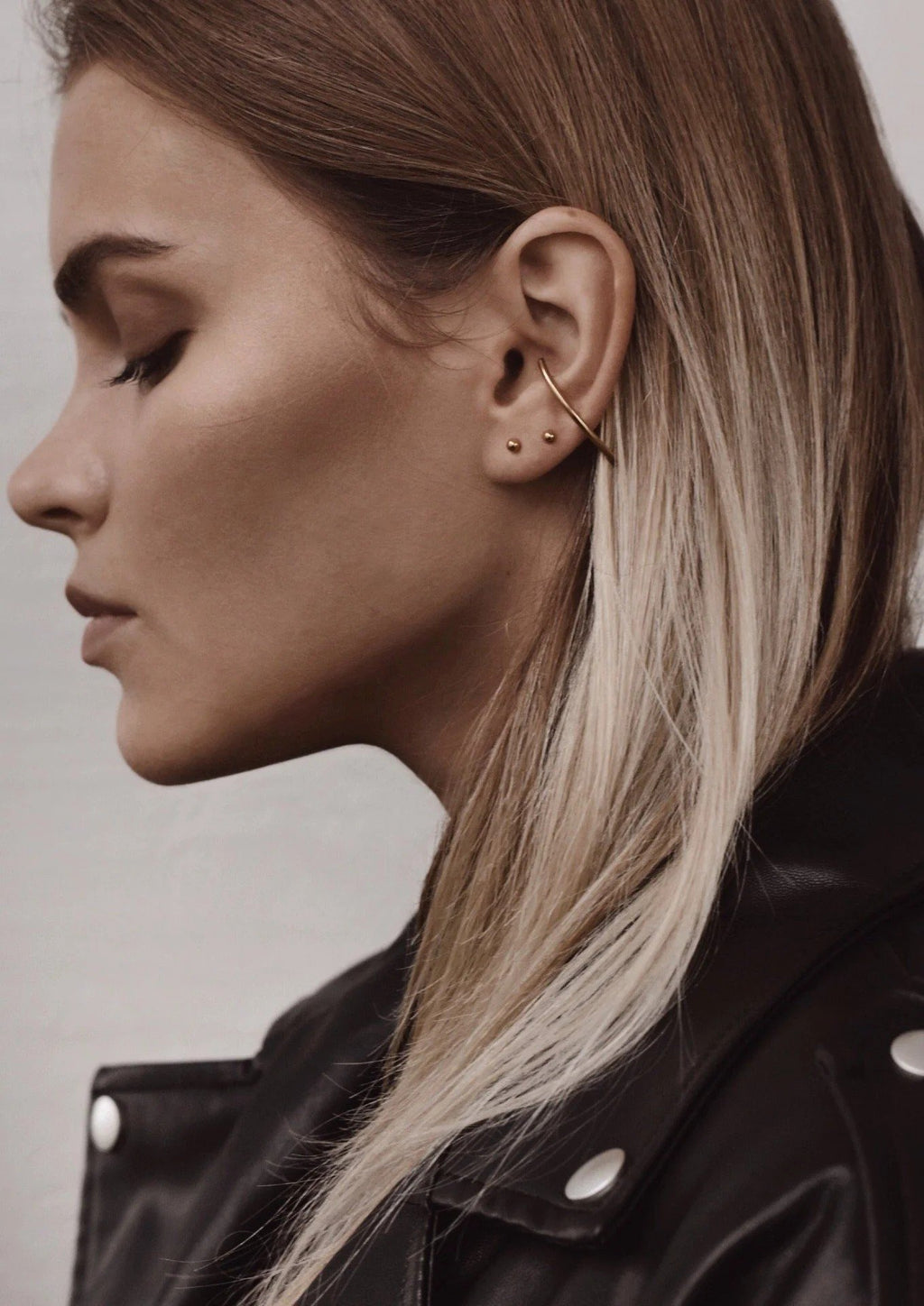 3. Side profile of woman wearing NO MORE Radius gold earrings, showcasing elegant curve