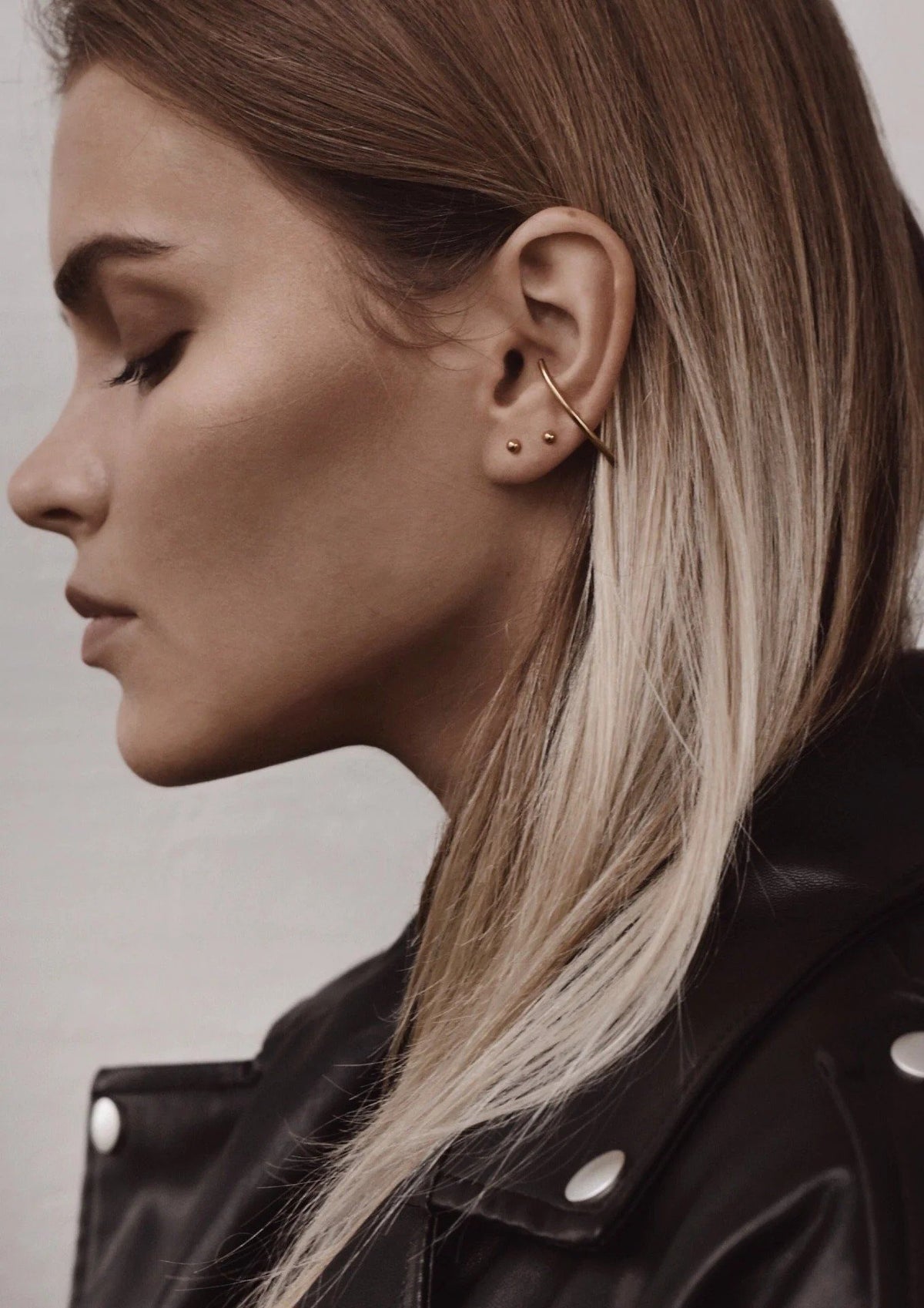 3. Side profile of woman wearing NO MORE Radius gold earrings, showcasing elegant curve