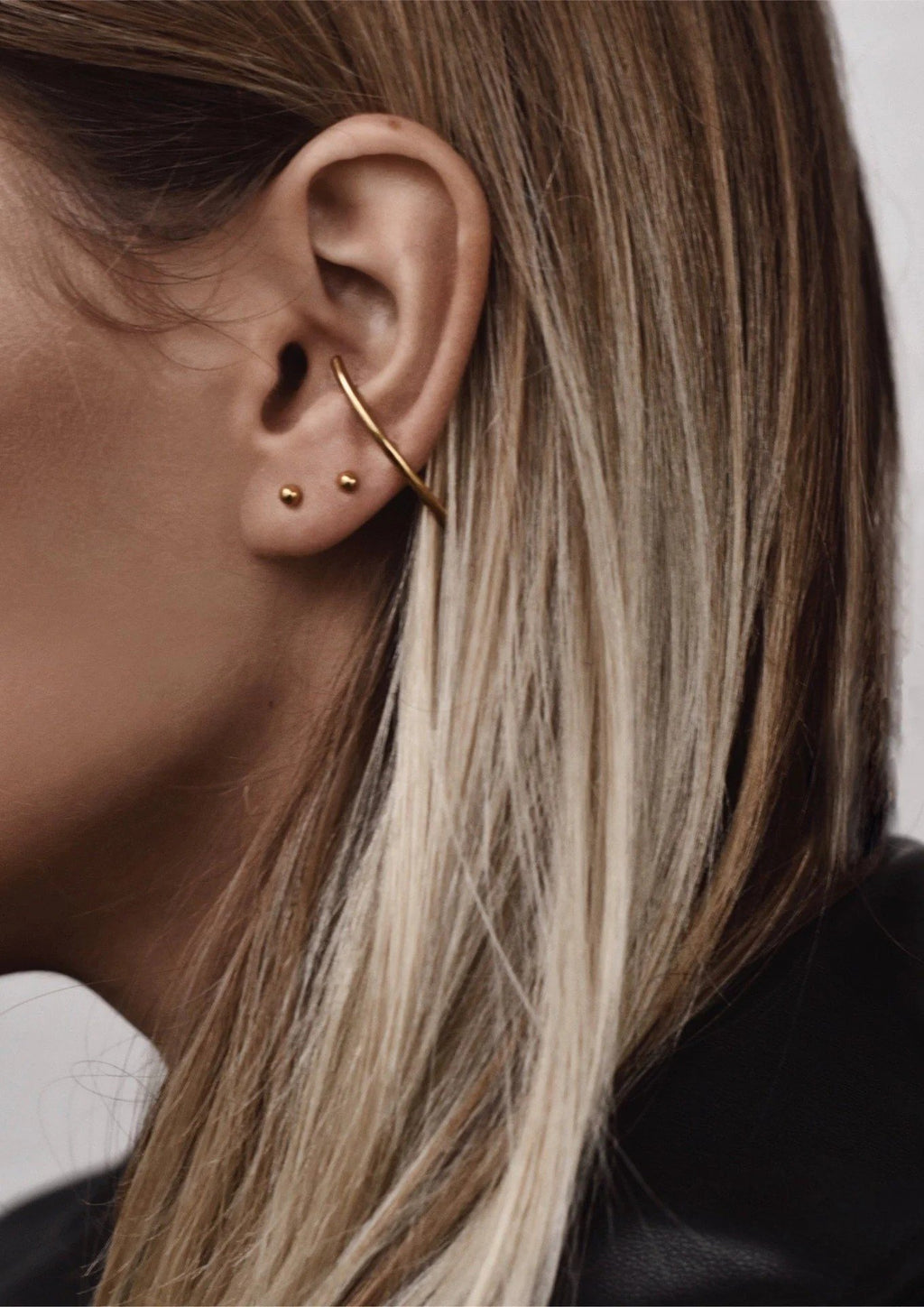 2. Close-up of woman wearing NO MORE Radius gold earrings, highlighting sleek design