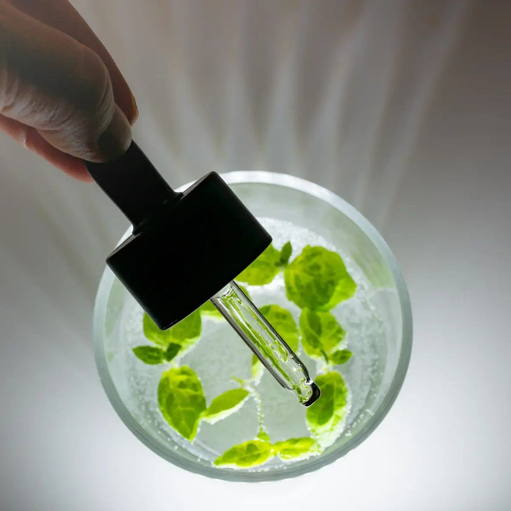 3. Close-up of Usva Cosmetics serum dropper with green leaves in a glass