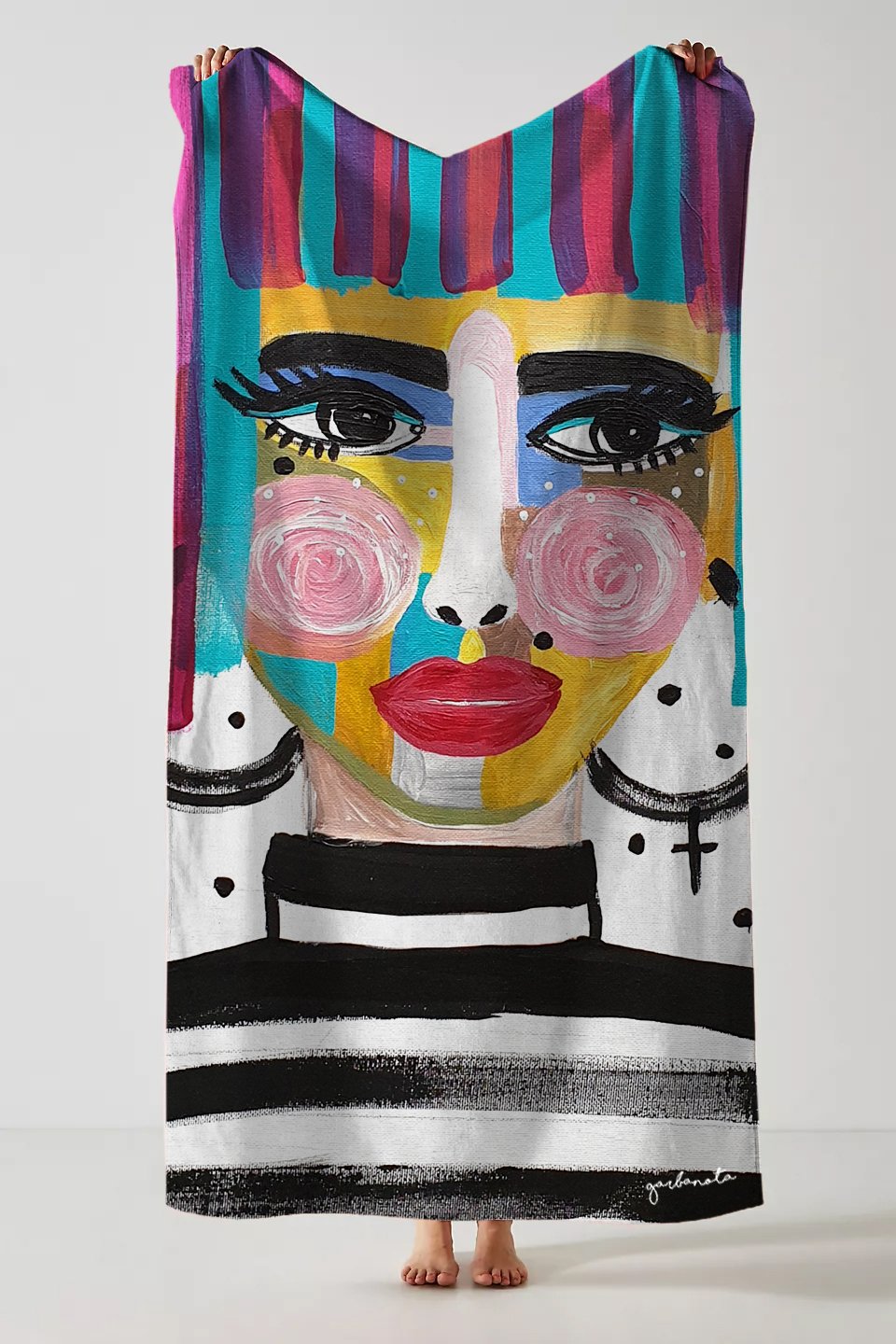 1. Garbanota Towel Roxana with artistic face design, held by a person, showcasing vibrant colors and unique pattern, made from cotton and polyester blend