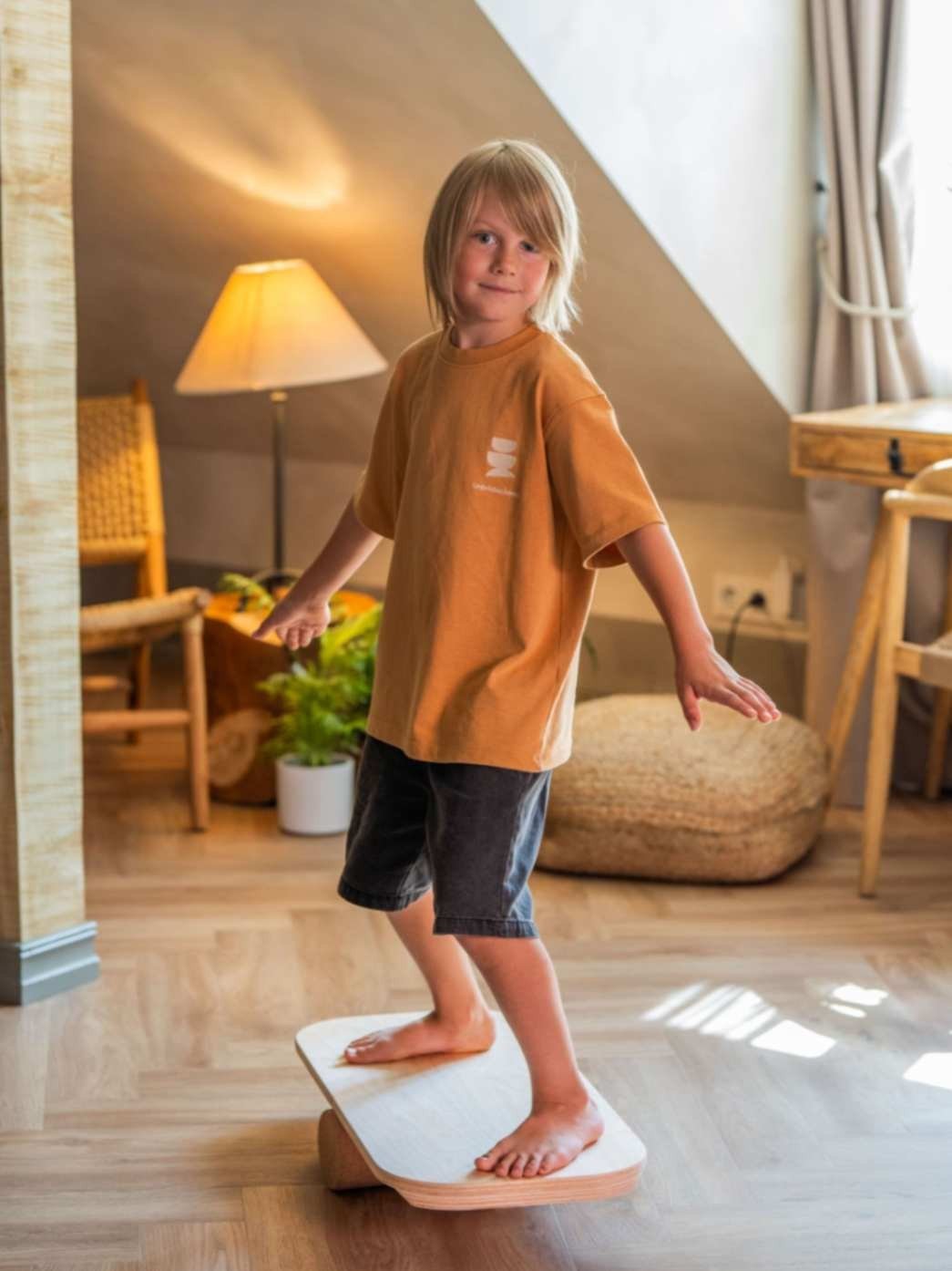 1. Child balancing on rectangular balance board with exercise roll in cozy room setting