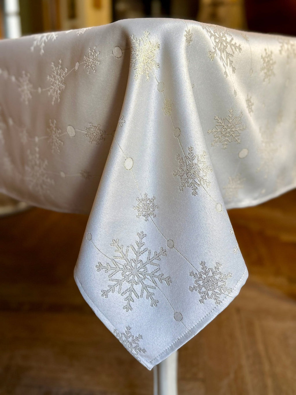 1. Rectangular tablecloth with golden snowflake design draped over table corner in warm indoor setting