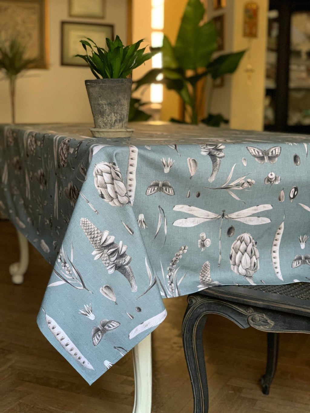 1. Rectangular table with aqua printed cotton tablecloth featuring botanical and insect designs in a cozy dining room setting