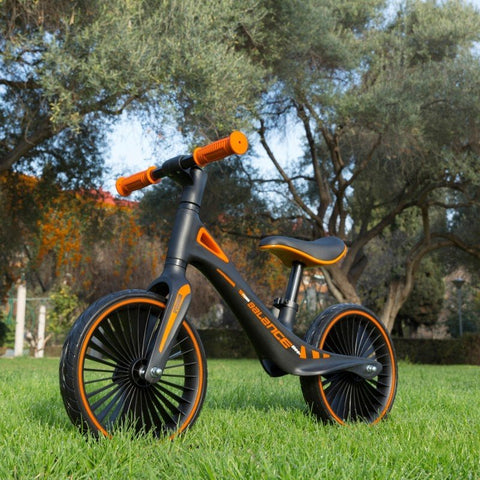 1. Feber balance bike on grass with trees in the background