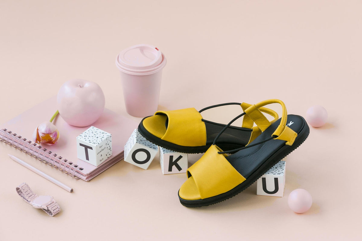 2. Lifestyle image of yellow Berlin sandals by Omaking, styled with pink and white accessories, highlighting summer fashion