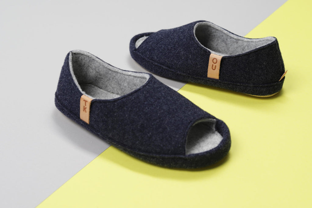 2. Pair of TOKU Bern Slippers in dark gray lambswool on a colorful background, highlighting open-toe design