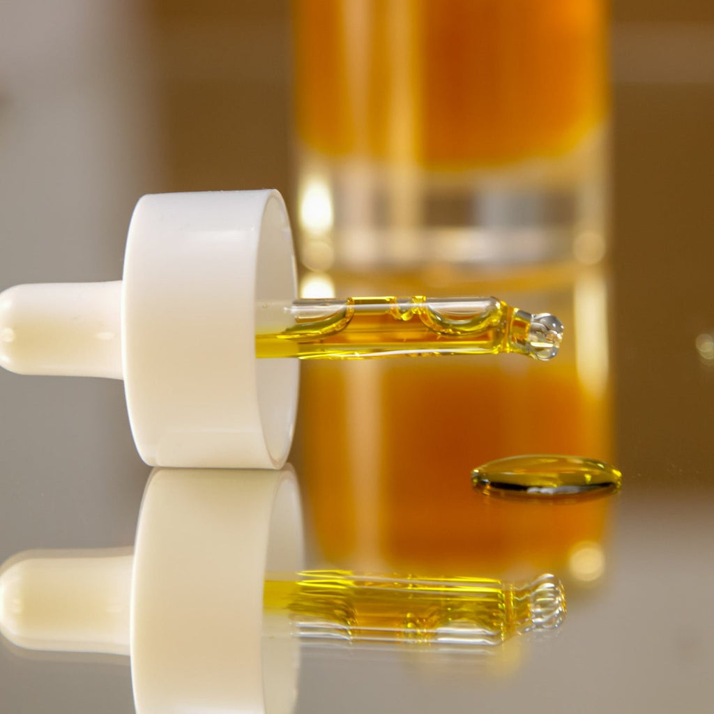 4. Close-up of Nörre Nordic REVIVE Face Oil Serum dropper with golden oil on reflective surface