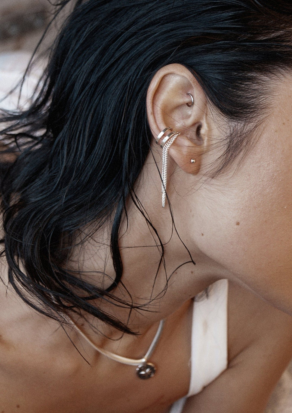 1. Woman wearing NO MORE Revolve silver ear cuff with double chain, styled in lifestyle setting
