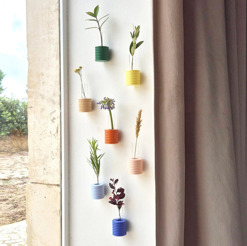 5. Assorted Ribble Wall Vases by 5mm Paper in multiple colors, displayed with flowers on a wall, lifestyle setting