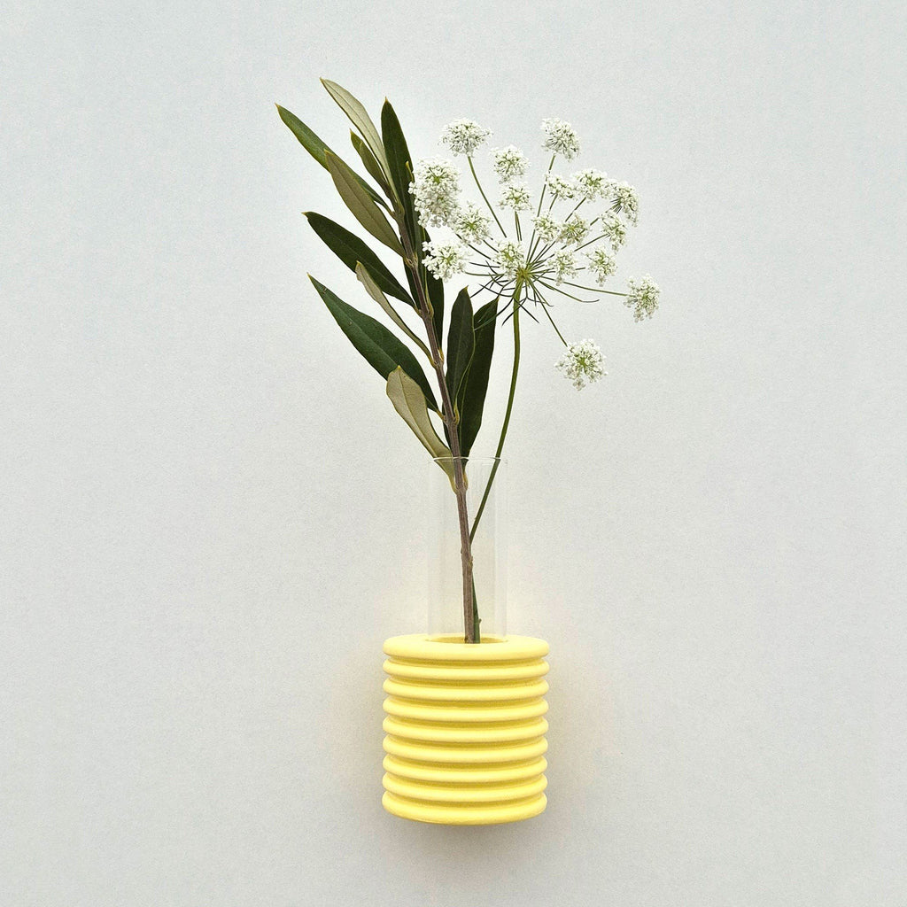 1. Yellow Ribble Wall Vase by 5mm Paper with white flowers, showcasing beech wood and water-based paint, lifestyle setting