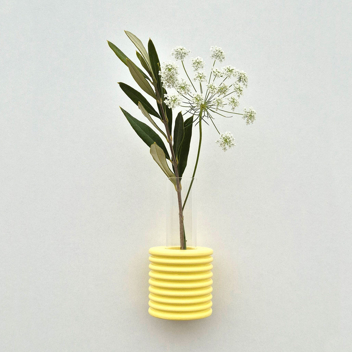 1. Yellow Ribble Wall Vase by 5mm Paper with white flowers, showcasing beech wood and water-based paint, lifestyle setting