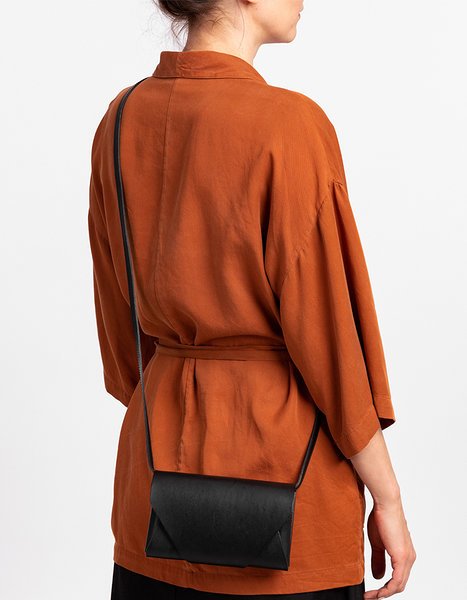 9. Woman wearing black leather Stella Soomlais Capital of Plenty clutch-wallet on back with orange jacket