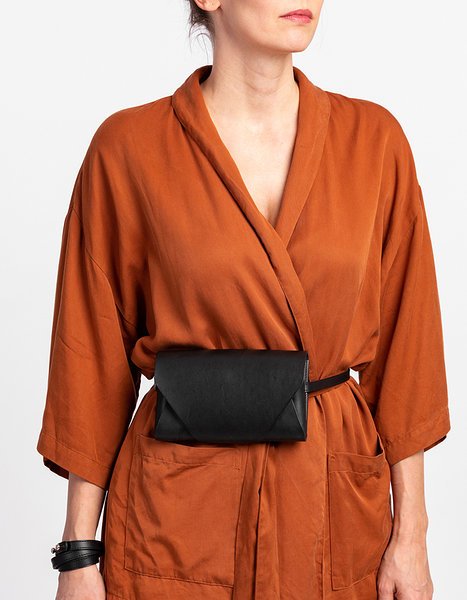 11. Woman wearing black leather Stella Soomlais Capital of Plenty clutch-wallet as belt bag with orange jacket