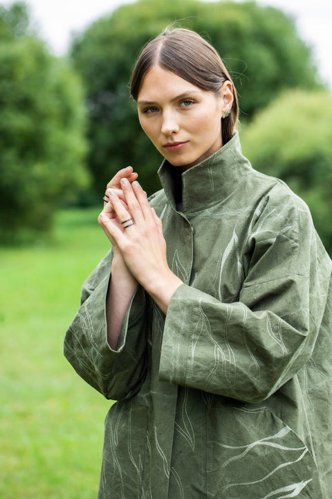 1. Woman wearing Lentsius stainless steel ring in a green outdoor setting, dressed in a green coat