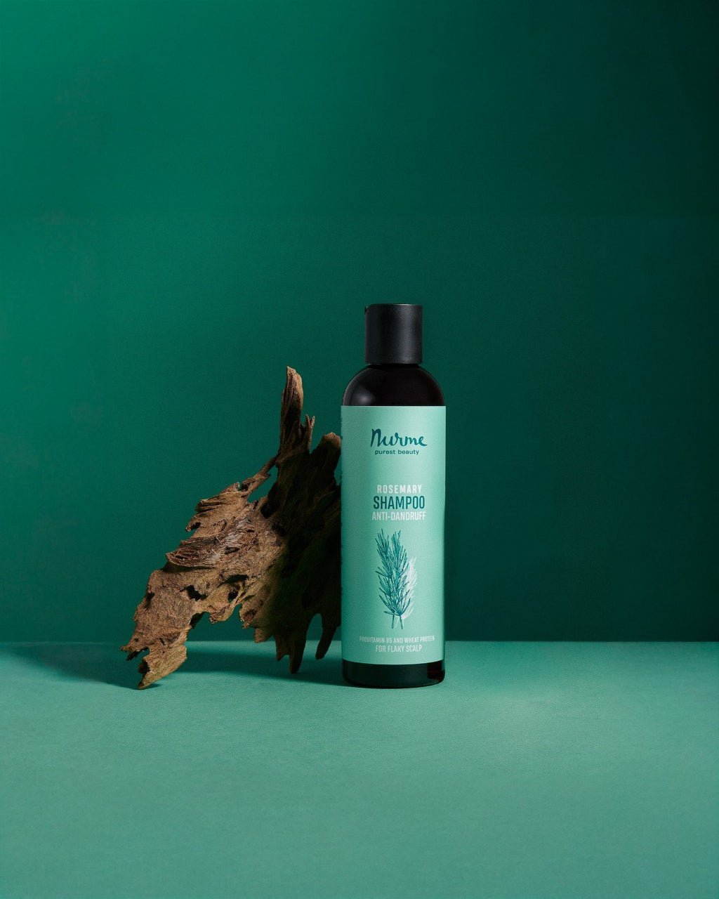 1. Nurme anti-dandruff rosemary shampoo bottle on green background with dried leaf accent