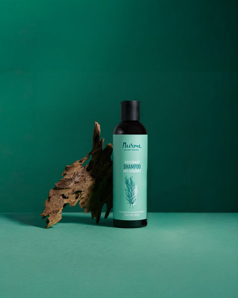 1. Nurme anti-dandruff rosemary shampoo bottle on green background with dried leaf accent