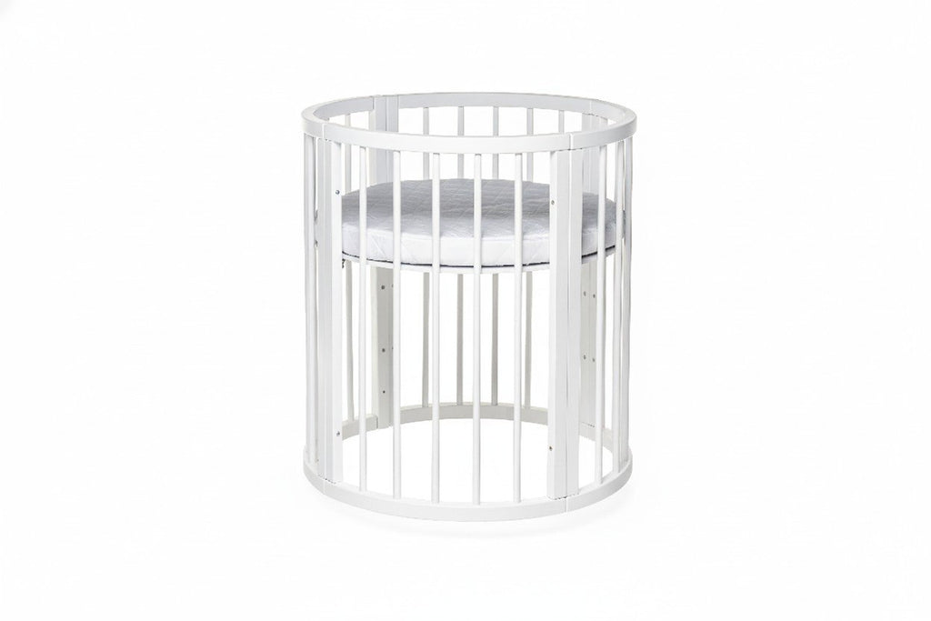 6. White round baby crib with high mattress setting, shown in a studio