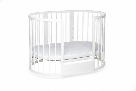 1. White round baby crib with lockable wheels and removable side, shown in a nursery setting