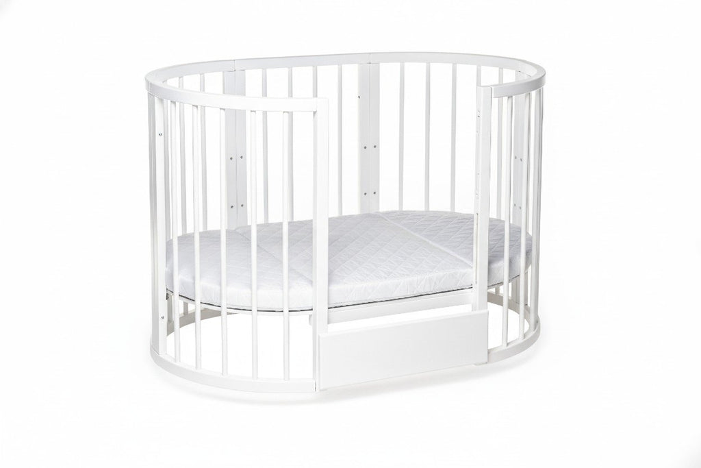 11. White round baby crib with mattress in studio setting, highlighting slatted design and removable side