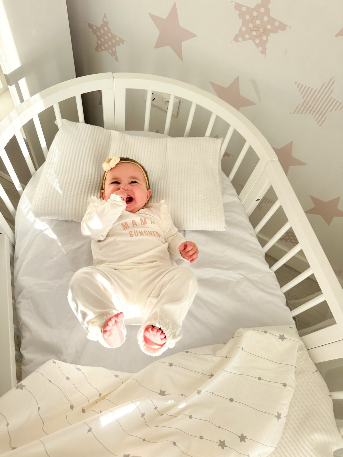 15. Baby lying in white round crib with star-patterned bedding