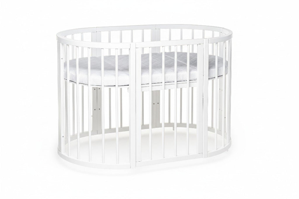 2. White round baby crib with adjustable mattress height, shown in a studio setting