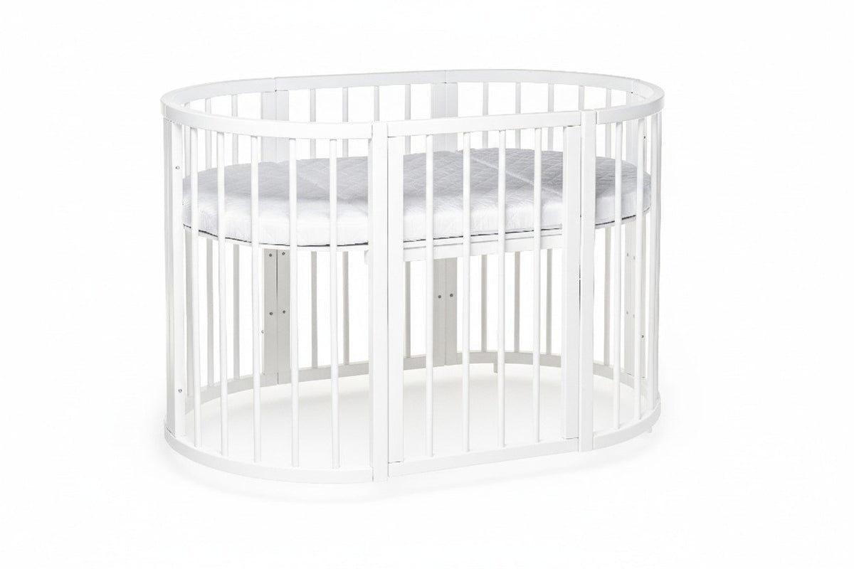 2. White round baby crib with adjustable mattress height, shown in a studio setting