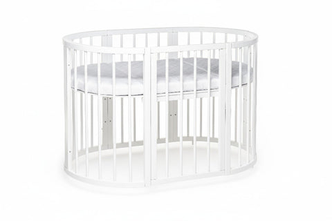 1. White round baby crib with mattress in studio setting, showcasing solid beechwood construction and slatted design