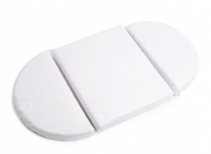 3. Close-up of white transforming mattress for round baby crib, highlighting orthopedic design