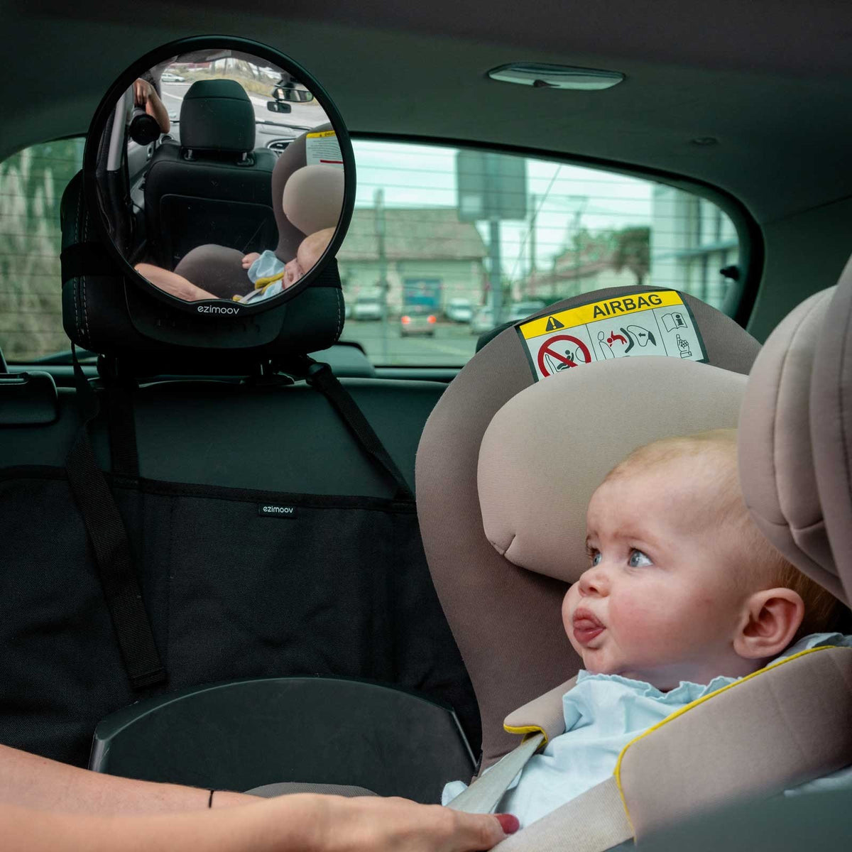 1. Baby in car seat with Ezimoov mirror on headrest showing rear view in car