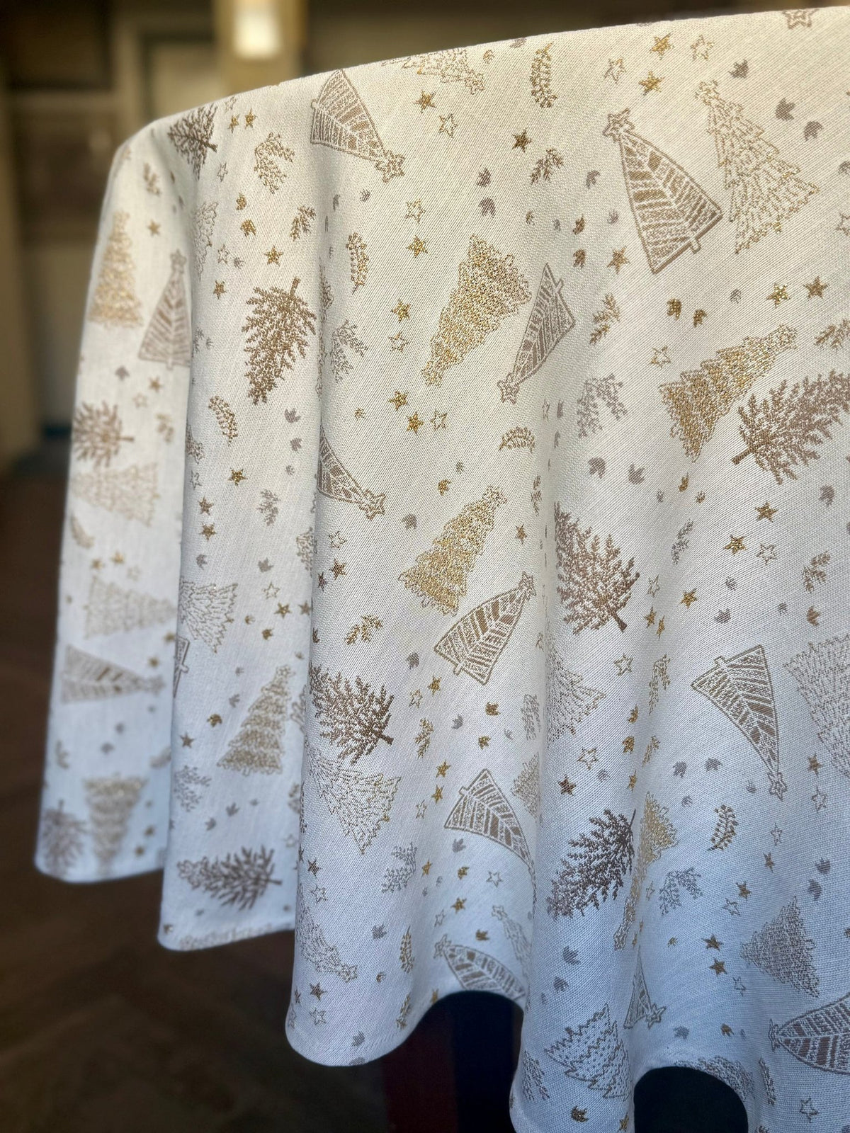 3. Close-up of Golden Forest tablecloth draped over table, highlighting intricate golden tree designs and festive elegance