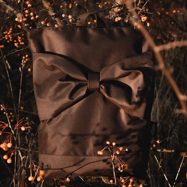4. MUNI waterproof brown backpack with bow displayed outdoors among autumn foliage