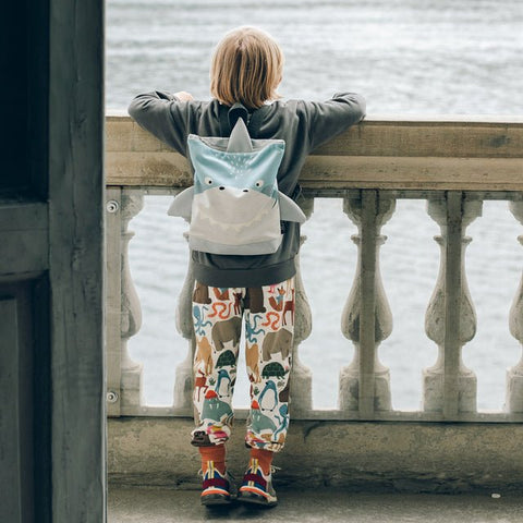 3. Child with Muni shark backpack leaning on railing, emphasizing outdoor exploration