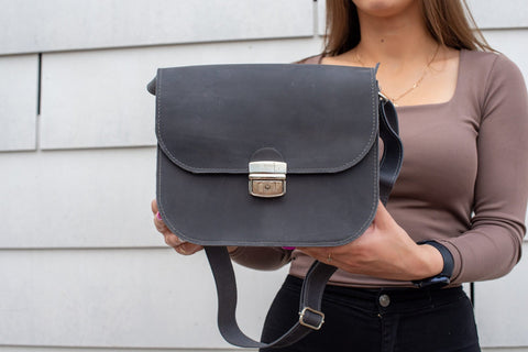 4. Close-up of Zelma Kraft grey leather saddle bag with buckle closure and keychain detail