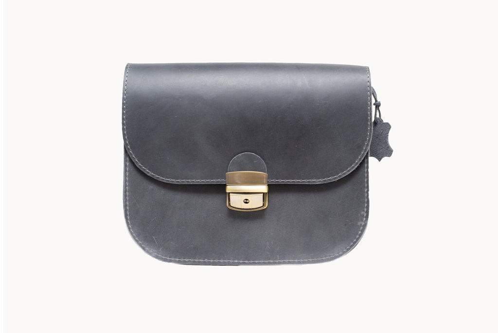 3. Studio shot of Zelma Kraft grey leather saddle bag with buckle closure and adjustable strap