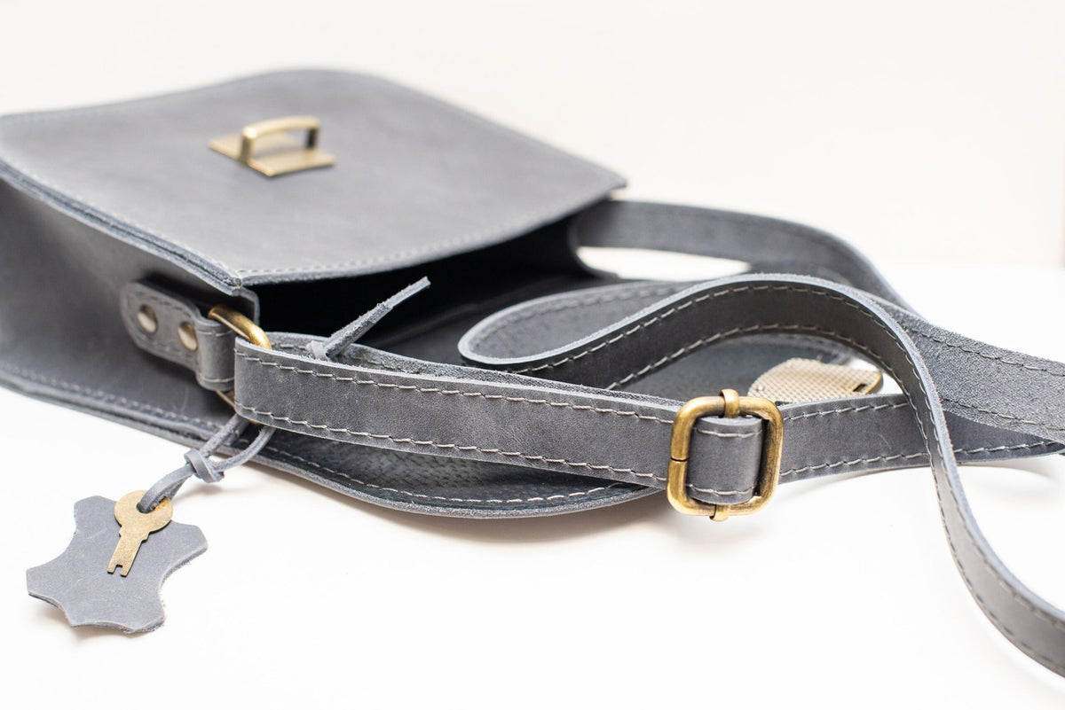 5. Close-up of Zelma Kraft grey leather saddle bag showing adjustable strap and buckle closure