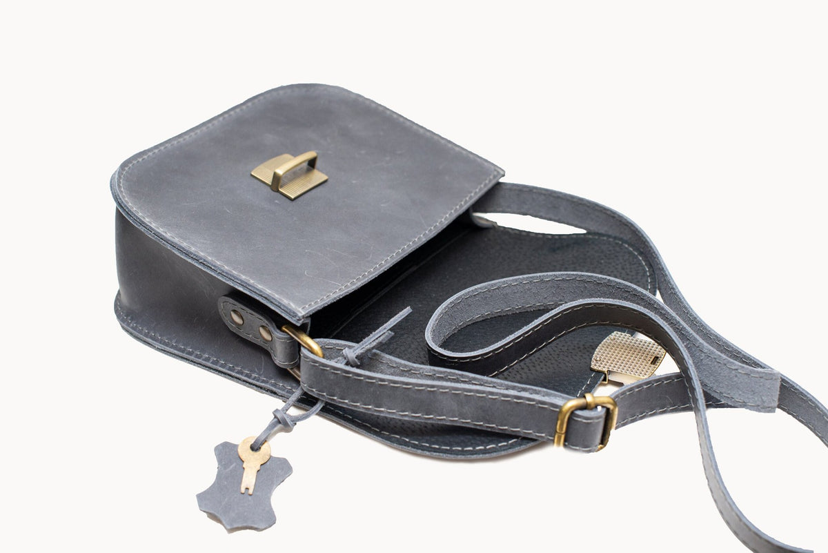 6. Woman wearing Zelma Kraft grey leather saddle bag in outdoor setting, shown from back