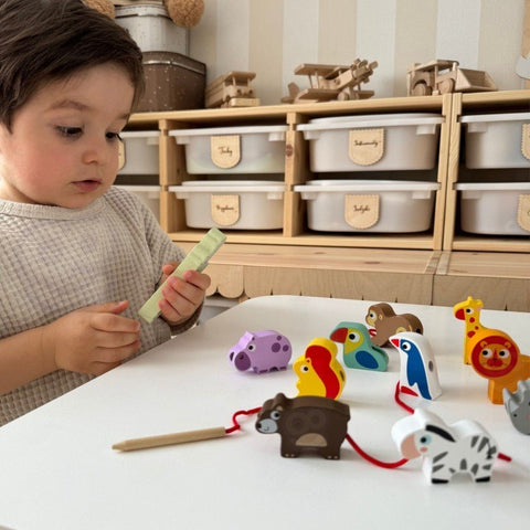 5. Child examining Woopie Let's Go Green safari animal threading blocks on a table