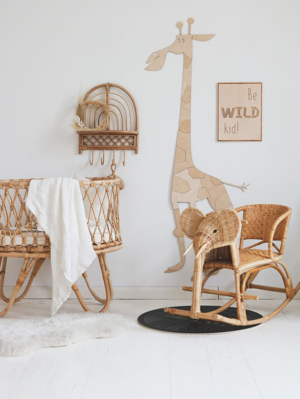 6. Wooden giraffe wall decoration in child's room with wicker furniture and 'Be Wild Kid' sign on white wall
