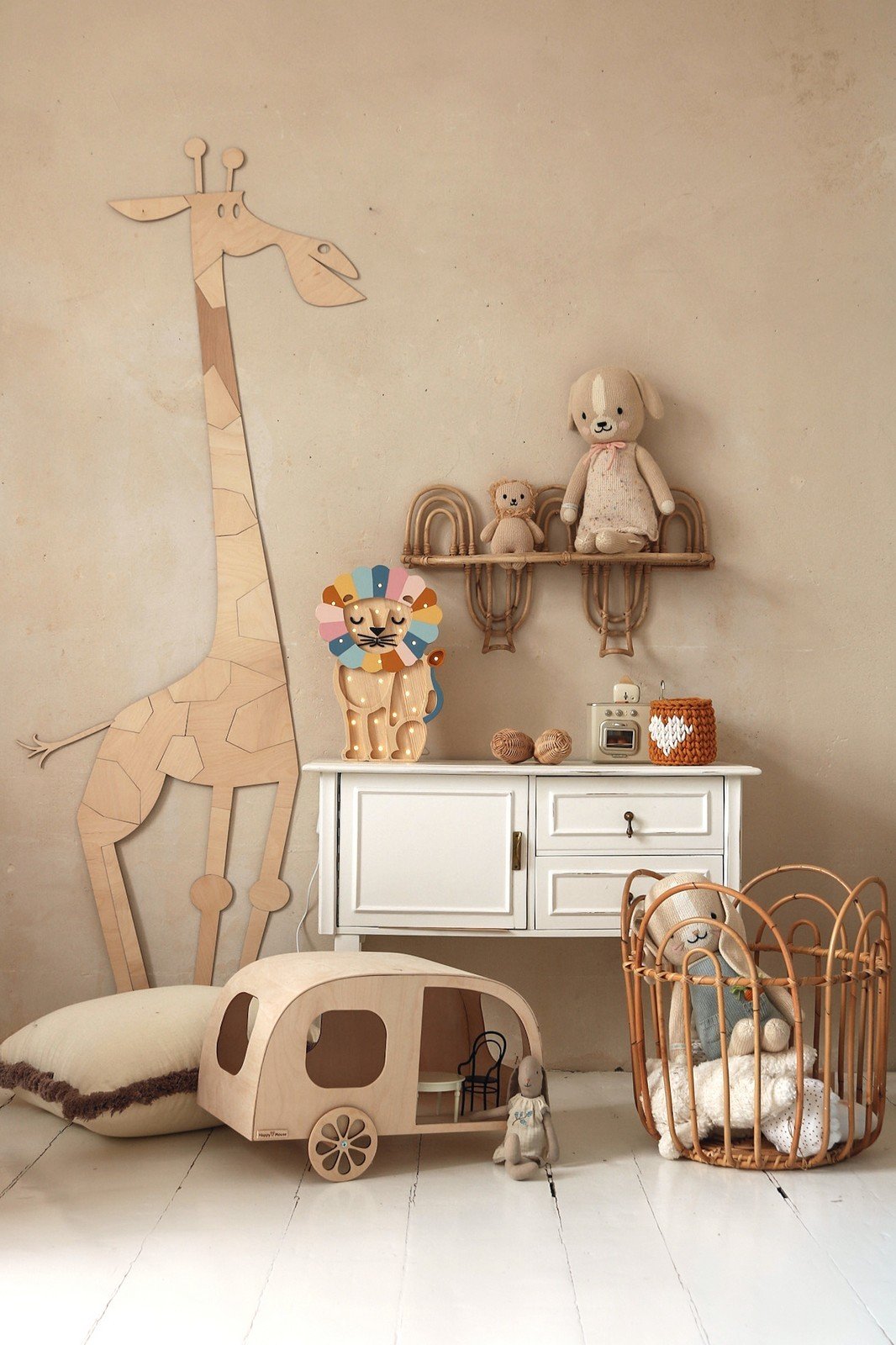 5. Wooden giraffe wall decoration in child's room with white cabinet, plush toys, and wicker basket on beige wall