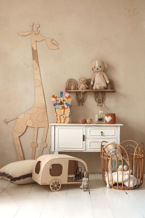 5. Wooden giraffe wall decoration in child's room with white cabinet, plush toys, and wicker basket on beige wall