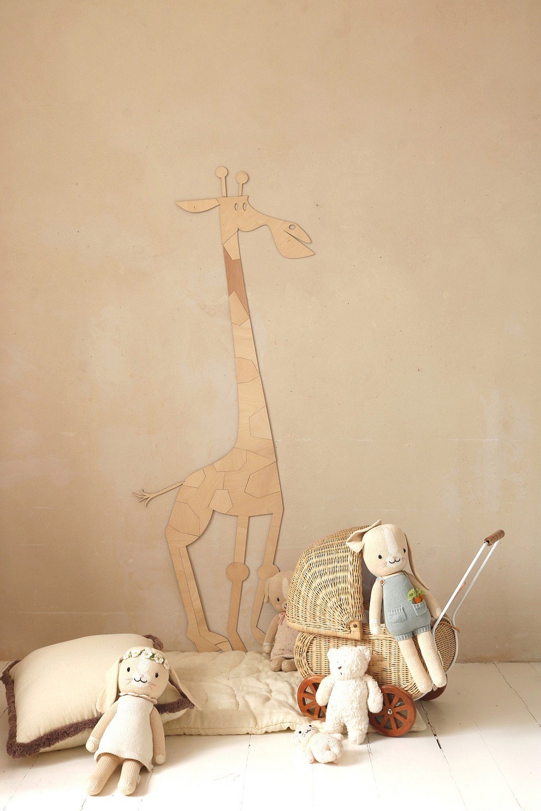 4. Wooden giraffe wall decoration in child's room with plush toys and wicker basket on beige wall