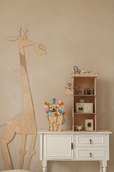 3. Wooden giraffe wall decoration next to white cabinet with colorful lion toy and small shelf in child's room