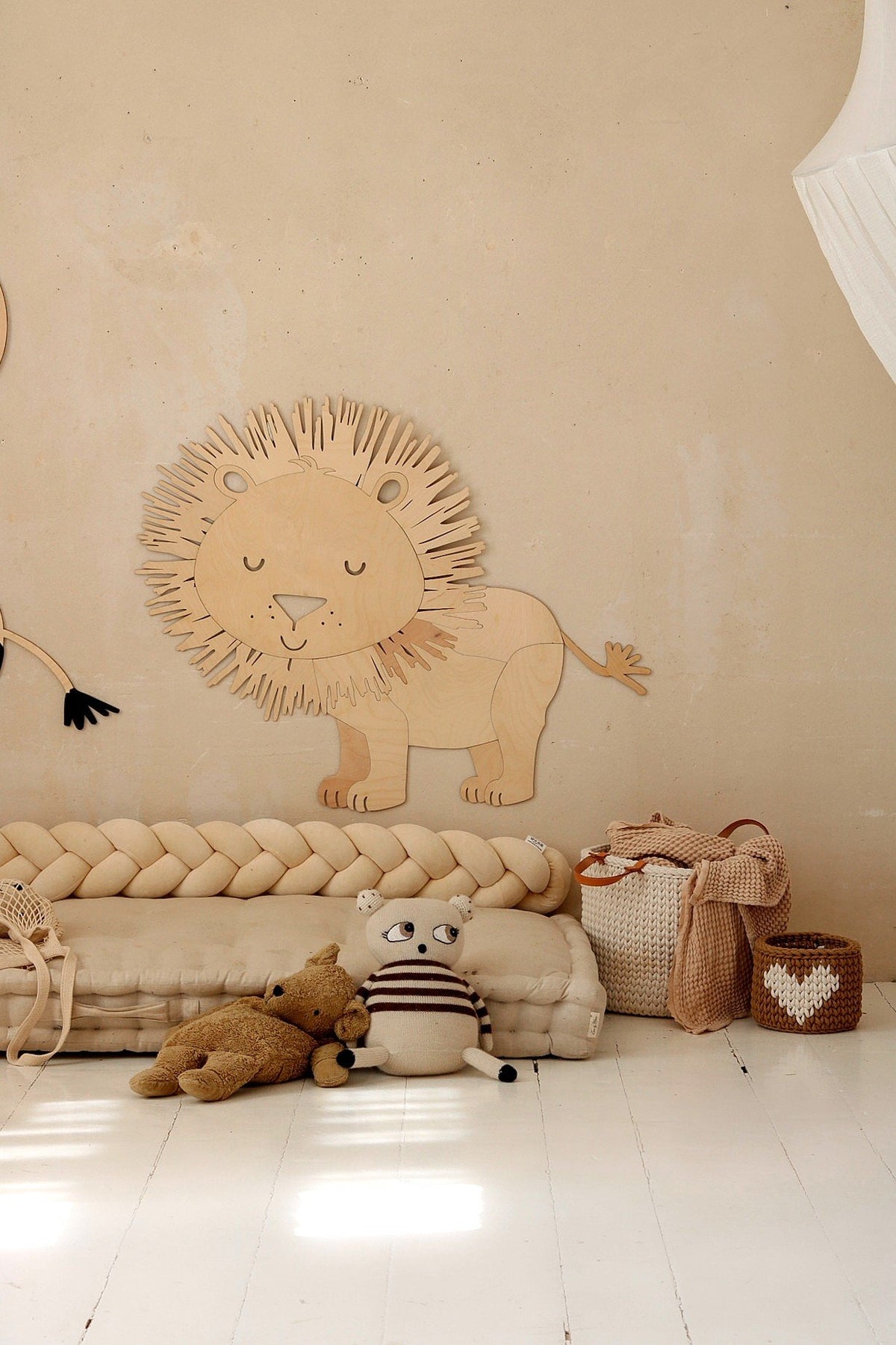 4. Wooden lion wall decoration above a beige braided cushion with stuffed toys