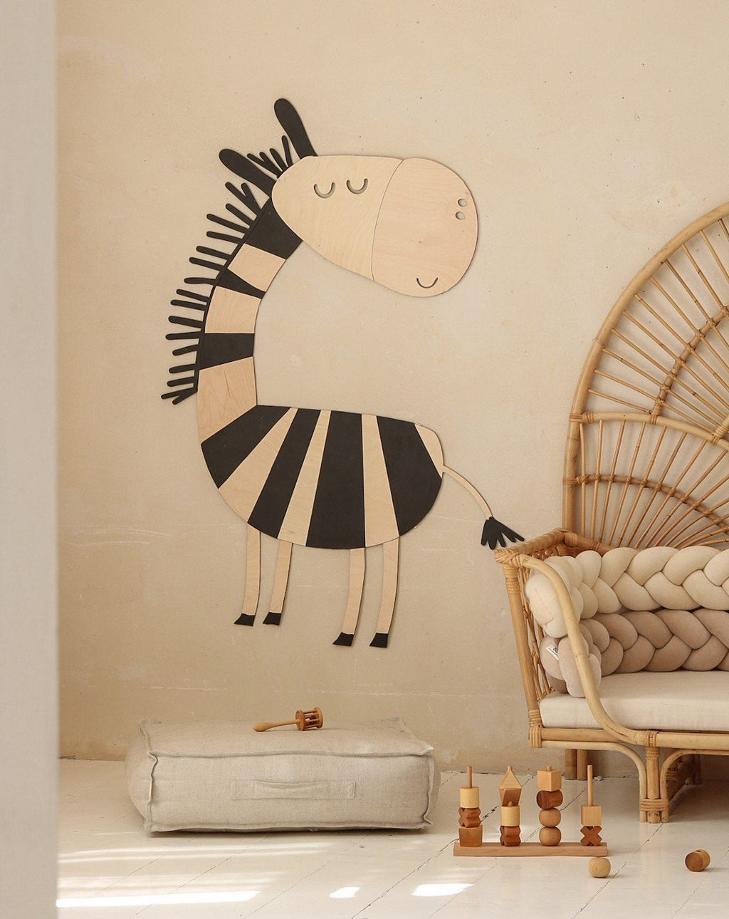 1. Wooden zebra wall decoration in a child's room with beige walls, next to a rattan chair and soft toys on the floor
