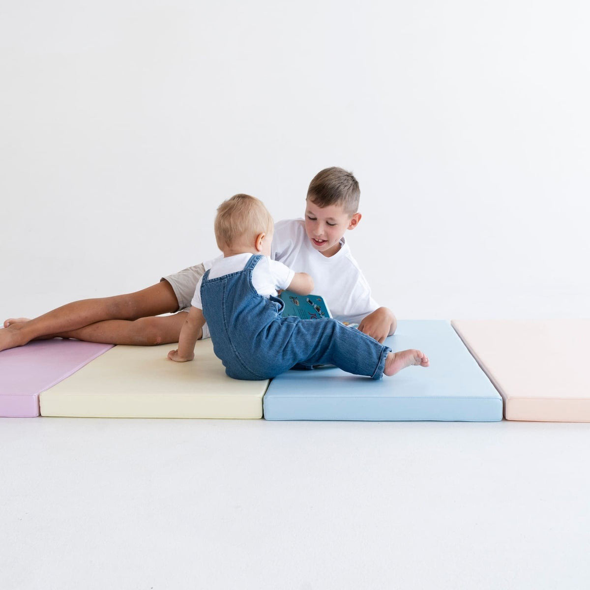 6. Two children interacting on pastel mats, fostering social skills and teamwork in a playful environment