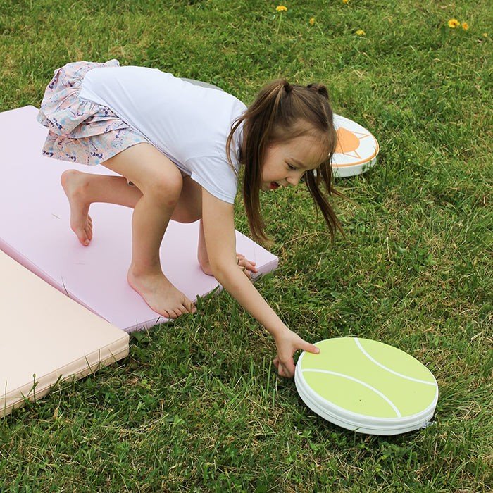 7. Girl playing on pastel mats outdoors, engaging in active play and creativity on grass