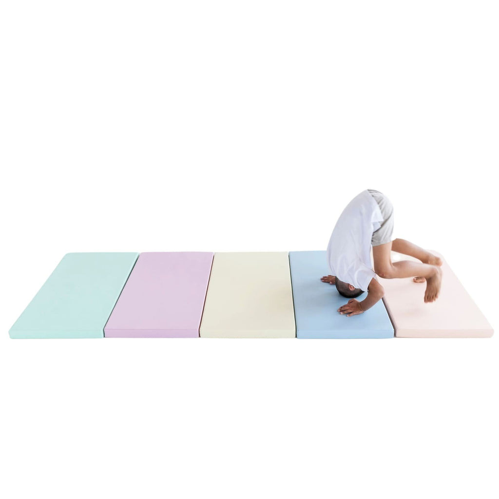 1. Child performing a headstand on IGLU's pastel-colored mat set, showcasing flexibility and playfulness in a bright setting